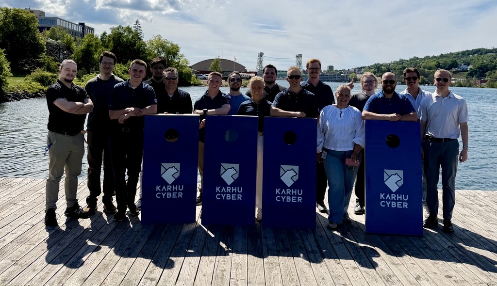 The Karhu Cyber team together on a waterfront dock with Karhu-branded cornhole boards